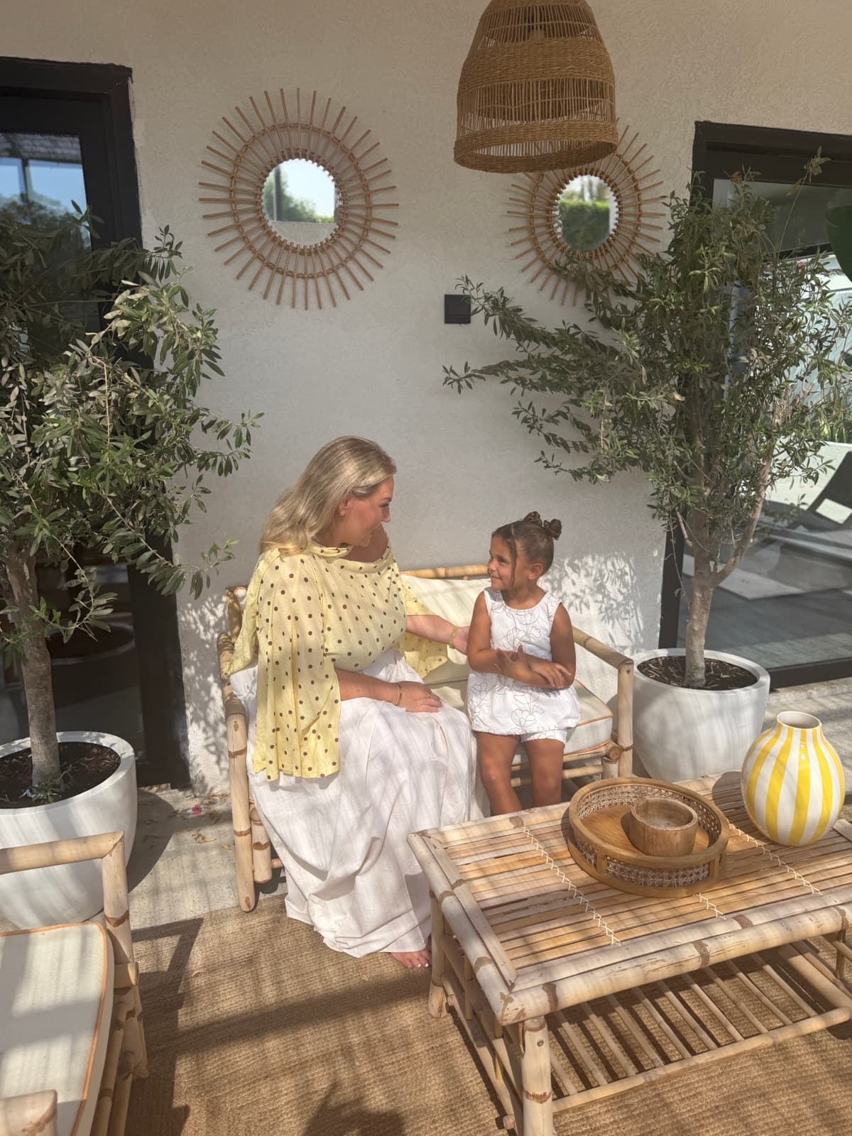 Two women and a child sitting together on a sofa on a sunny terrace
